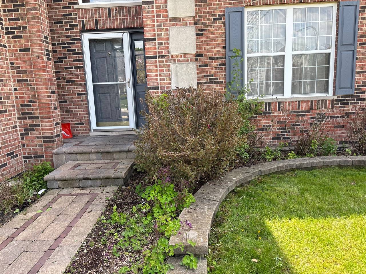 Brick Naperville home with shrubs, a front landscape bed, and yard cleanup work in progress
